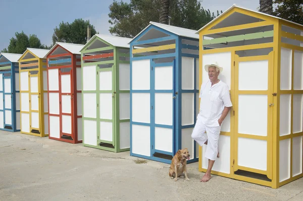 Cabanas de praia coloridas e homem sênior com cão — Fotografia de Stock