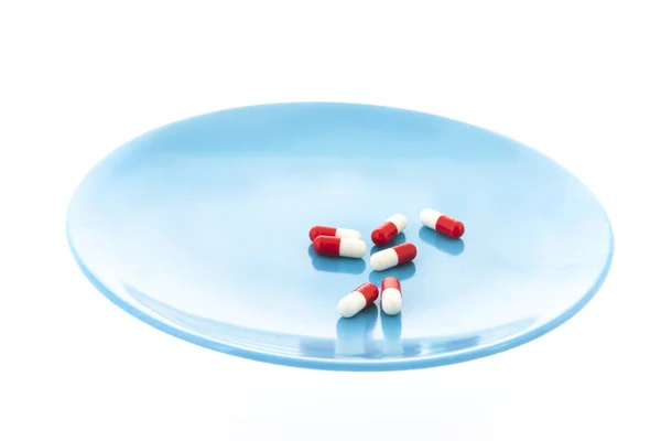 Capsules in red and white on plate — Stock Photo, Image
