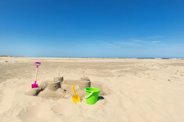 Castello di sabbia con giocattoli in spiaggia — Foto Stock