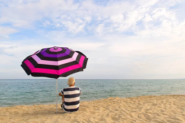 Muž pod plážovým deštníkem pro stín — Stock fotografie