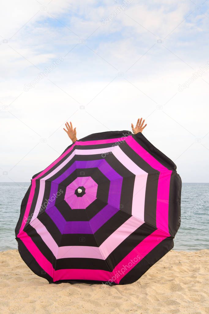 Happy at thbe beach behind Beach umbrella for shadow