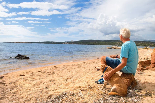 Homem com cão na costa da Córsega com torre genovesa — Fotografia de Stock