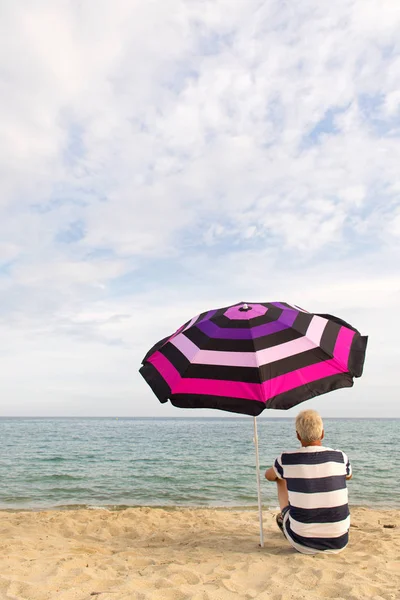 Man under beach umbrella for shadow — 스톡 사진