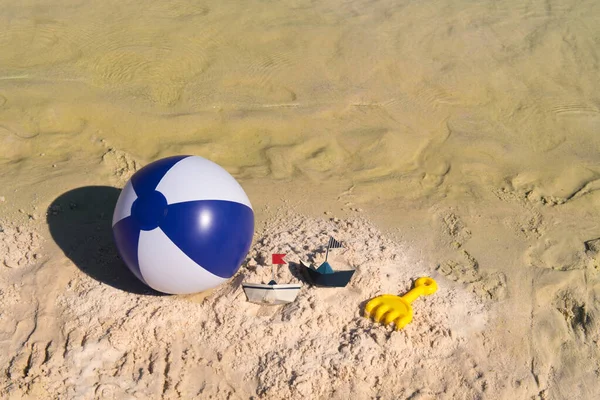 ビーチでボールと紙のボートとしていくつかのおもちゃ — ストック写真