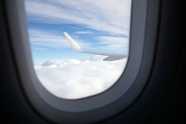 Wing of airplane above clouds from its cabin — Stok fotoğraf