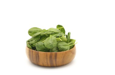 Beyaz zemin üzerinde ahşap bir kasede taze çiğ ıspanak ve geniş bir kopya alanı..
