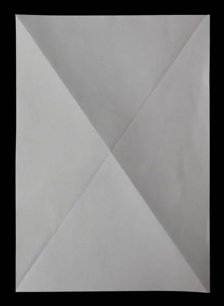 White sheet of paper diagonaly folded in four on black — Stock Photo, Image