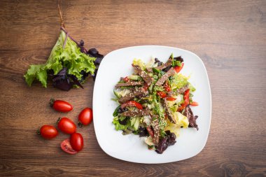 Taze salata, ızgara biftek, roka ve domates. Üst görünüm
