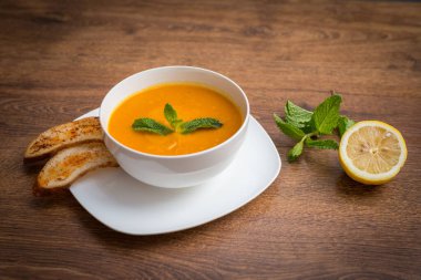 Baharatlı mercimek çorbası, otlar, rustik metal tencere ve kaselerde ekmek, ahşap fon, üst manzara..