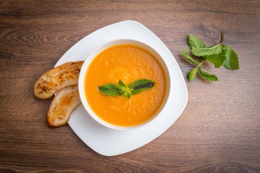 Baharatlı mercimek çorbası, otlar, rustik metal tencere ve kaselerde ekmek, ahşap fon, üst manzara..