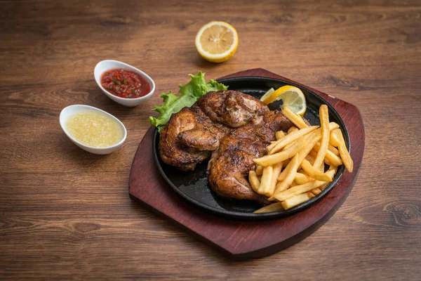 Fried chicken of tapaka in a pan with fries and sauces