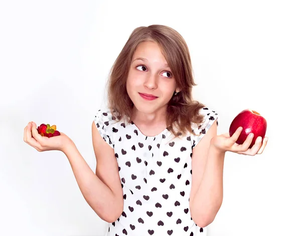 Mädchen Entscheidet Sich Zwischen Bonbons Und Apfel Stockbild