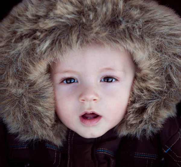 Der Kleine Junge Mit Der Pelzigen Kapuze Auf Dem Kopf lizenzfreie Stockfotos