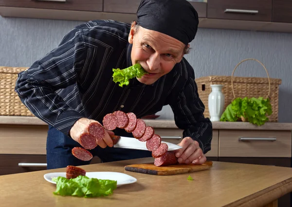 Мужчина режет колбасу — стоковое фото