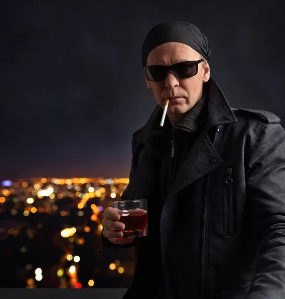 Man met een goed glas whisky op de achtergrond van de nacht stad — Stockfoto