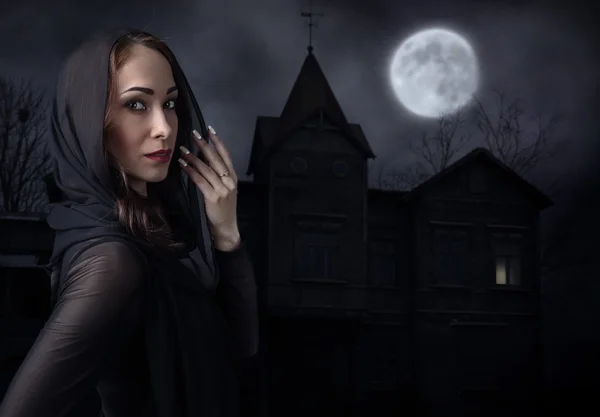 在月光下的夜色老房子前的黑衣女人 — 图库照片