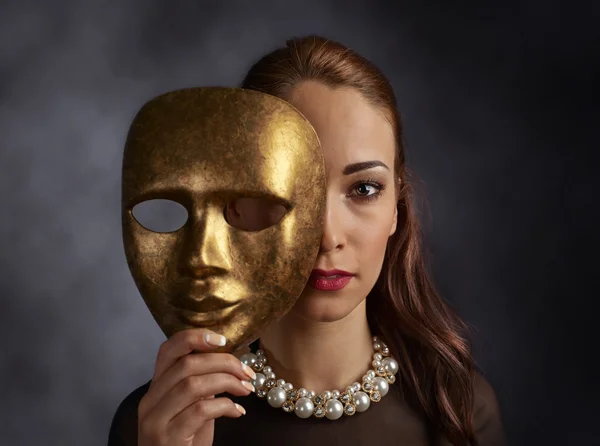 Femme dans une robe noire avec un collier de perles et un vieux masque — Photo