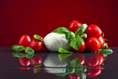 Yeşil fesleğenli Mozzarella ve siyah masadaki domatesler