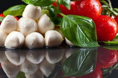 Yeşil fesleğenli Mozzarella ve siyah masadaki domatesler