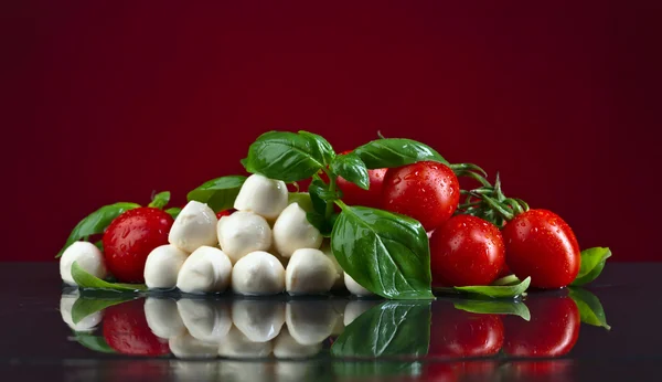 Mozzarella met groene basilicum en tomaten op zwarte tafel — Stockfoto