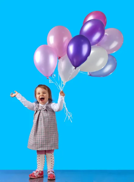 Klein meisje met ballonnen op een blauwe achtergrond — Stockfoto