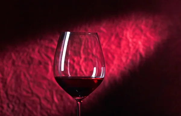 Garrafa e copo de vinho tinto em um fundo escuro — Fotografia de Stock
