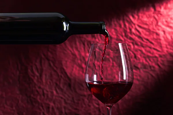 Botella y copa de vino tinto sobre fondo oscuro — Foto de Stock