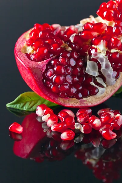Broken ripe pomegranate with leaves — Stock Photo, Image