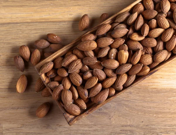 Almonds in old wooden dish — Stock Photo, Image