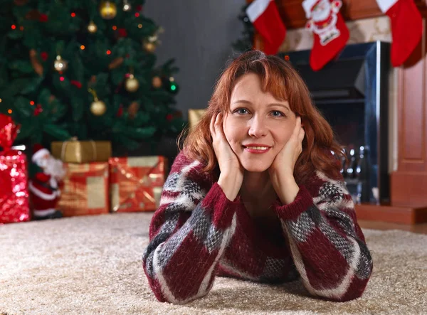 woman on the carpet in the room with fireplace and Christmas dec