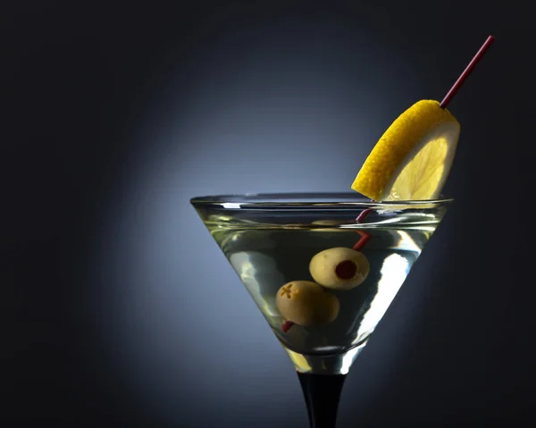 Martini con limón y aceitunas verdes sobre fondo negro — Foto de Stock