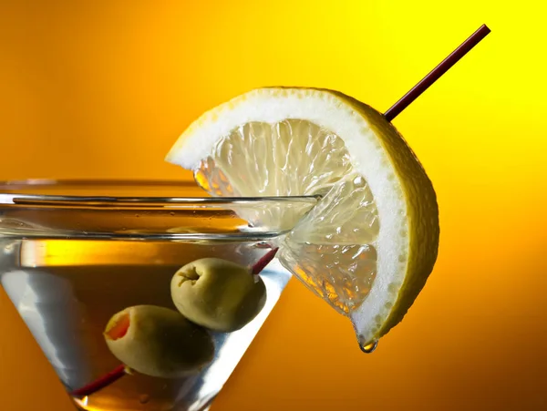 Martini, citrom, zöld olajbogyó, sárga háttérrel — Stock Fotó