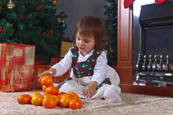 Маленькая девочка с мандаринами в комнате с рождественскими украшениями — стоковое фото