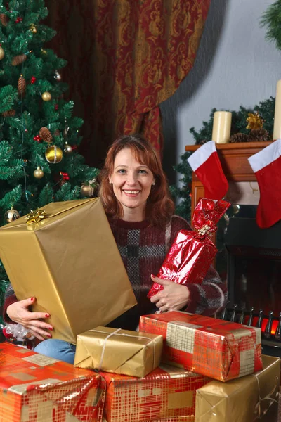 Kvinna med gåvor i rummet med öppen spis och jul decora — Stockfoto
