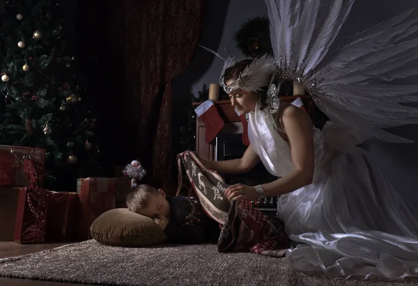 Λευκό άγγελος και ύπνου αγόρι κοντά στο χριστουγεννιάτικο δέντρο — Φωτογραφία Αρχείου