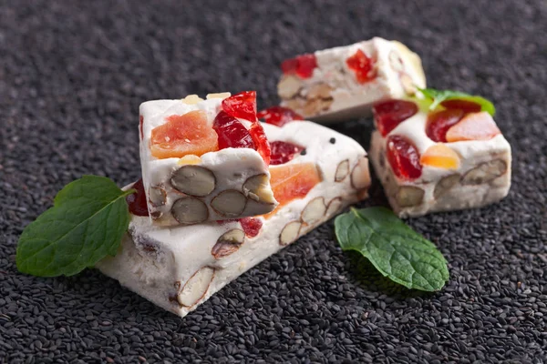 Soft nougat with tropical fruit and berries on black sesame — Stock Photo, Image