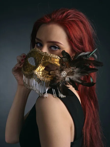 Schöne Frau mit goldener Karnevalsmaske auf schwarzem Hintergrund — Stockfoto