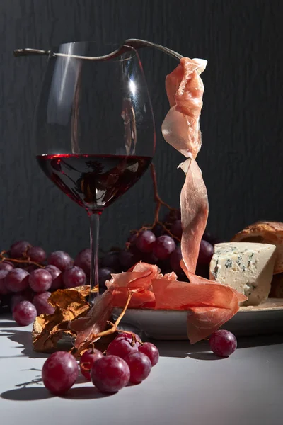 Jamon , cheese , grape and red wine on the kitchen table — Stock Photo, Image