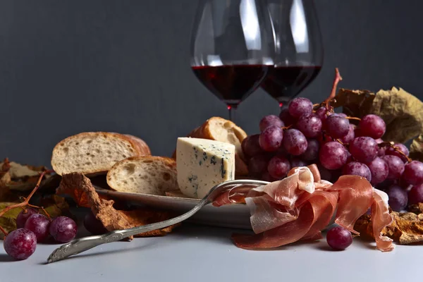 Jamon, queijo, uva e vinho tinto na mesa da cozinha — Fotografia de Stock