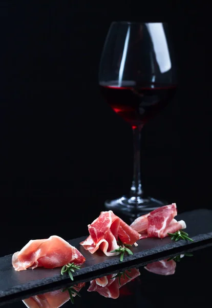Jamon a červené víno na černém pozadí — Stock fotografie