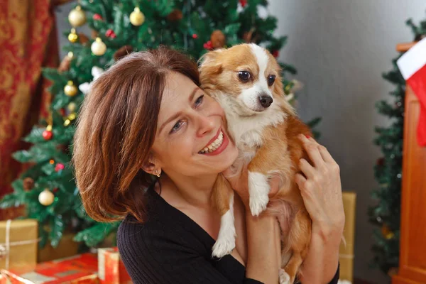 Frau mittleren Alters mit Hund im weihnachtlich dekorierten Zimmer — Stockfoto