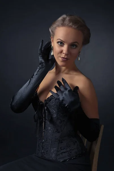 Молода красива жінка в чорному корсеті з перловими сережками — стокове фото