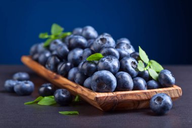 ahşap tabak içinde yeşil yaprakları ile yaban mersini 