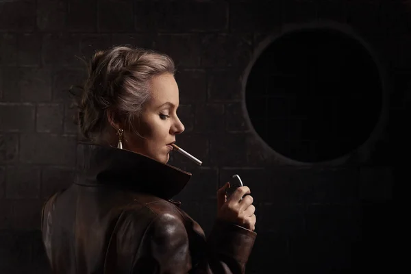 Kadın kahverengi deri ceket çakmak ve sigara ile — Stok fotoğraf