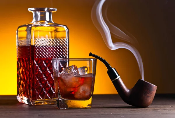 Whiskey and pipe on a wooden table — Stock Photo, Image