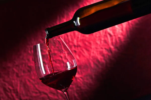 Botella y copa de vino tinto sobre fondo oscuro — Foto de Stock