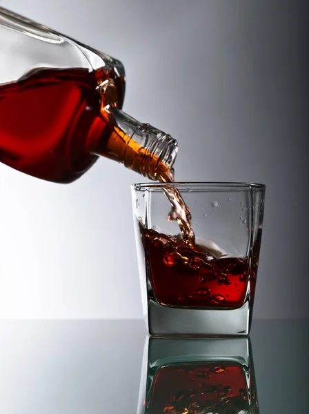 Garrafa e copo de uísque em uma mesa de vidro — Fotografia de Stock