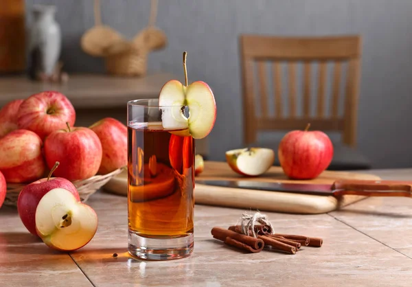 Glas äppeljuice och mogna rosa äpplen på ett köksbord — Stockfoto