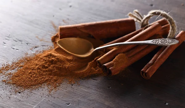 Cinnamon sticks and powder on a wooden table — Stock Photo, Image