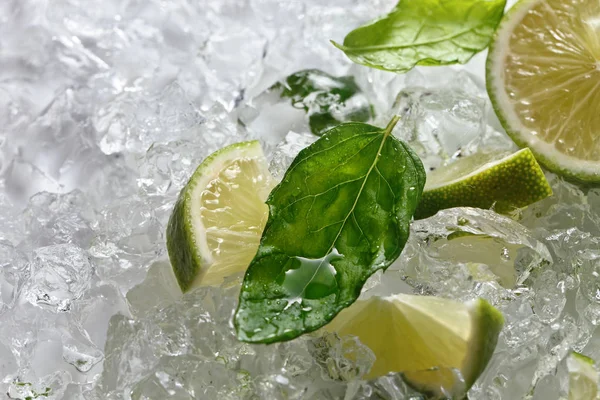 Rodajas de lima y hojas de menta sobre hielo — Foto de Stock